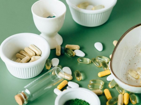 pexels-photo-7615570-7615570 Assorted natural supplements and pills in ceramic bowls on a green background, showcasing health and wellness themes.